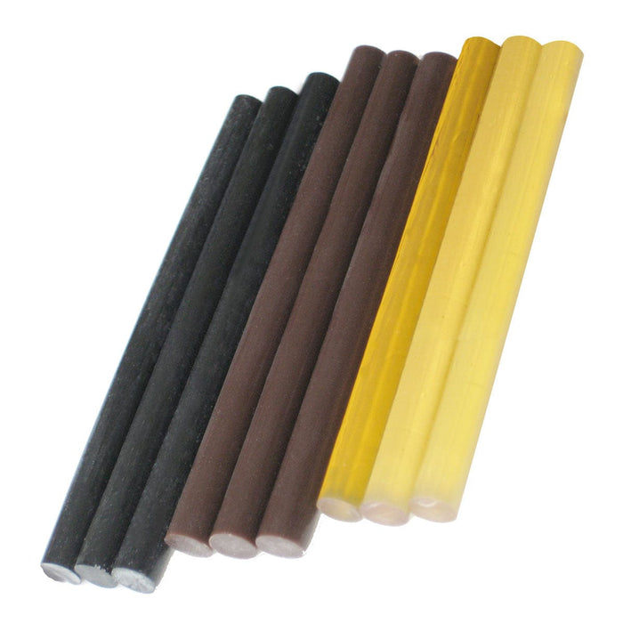 Nine cylindrical glue sticks—three black, three brown, and three transparent yellow—are arranged side by side on a white background.