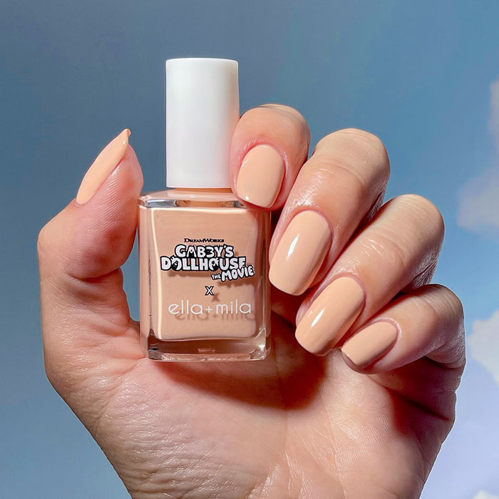 Gabby's Dollhouse peach nail polish manicure on a medium skin tone, holding the bottle