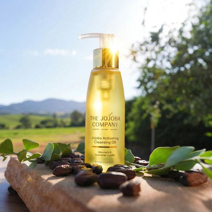Jojoba Activating Cleansing Oil bottle from The Jojoba Company on a natural background with leaves and seeds.