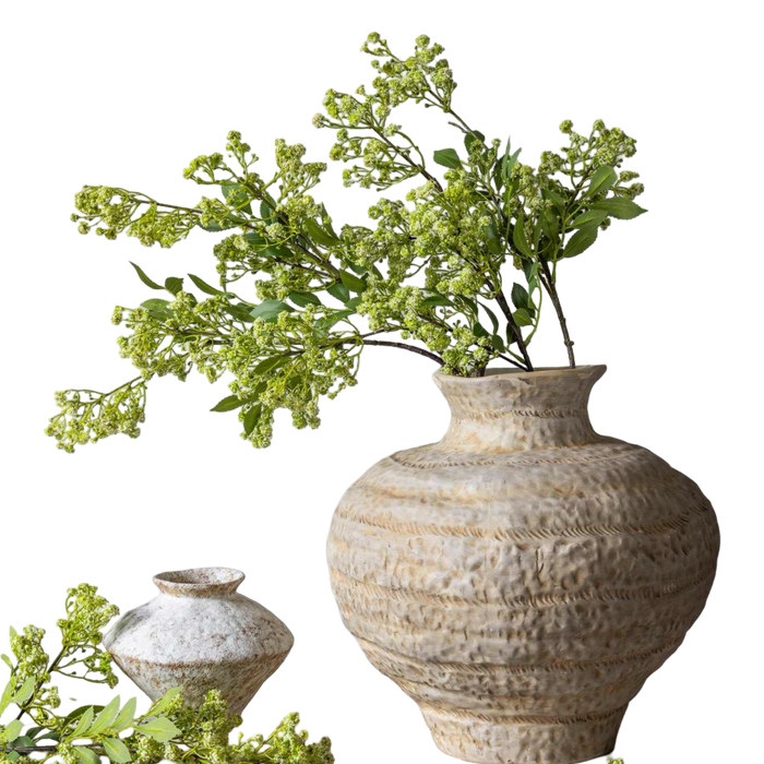 Decorative textured vase with greenery on a white background