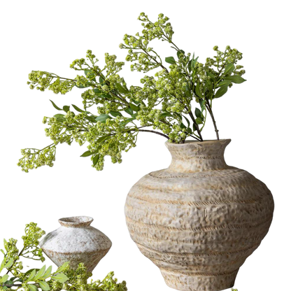 Decorative textured vase with greenery on a white background