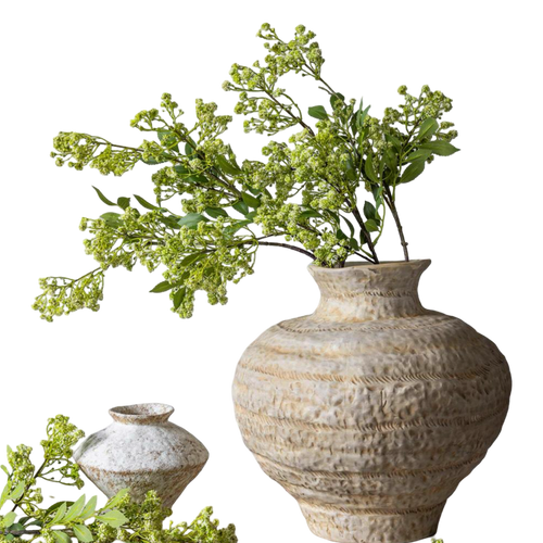 Decorative textured vase with greenery on a white background