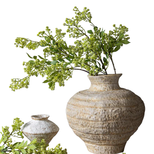 Decorative textured vase with greenery on a white background