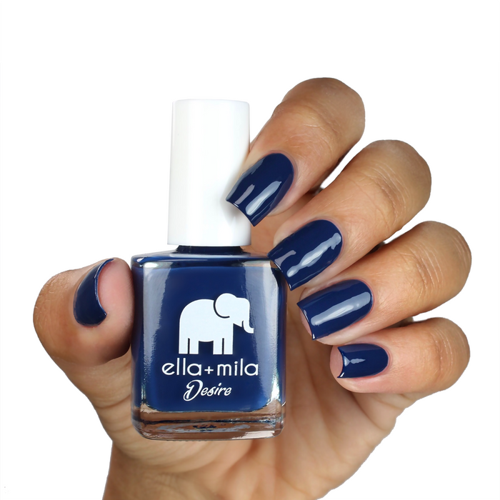 Blindfold Me deep navy nail polish on a medium skin tone, hand holding the bottle