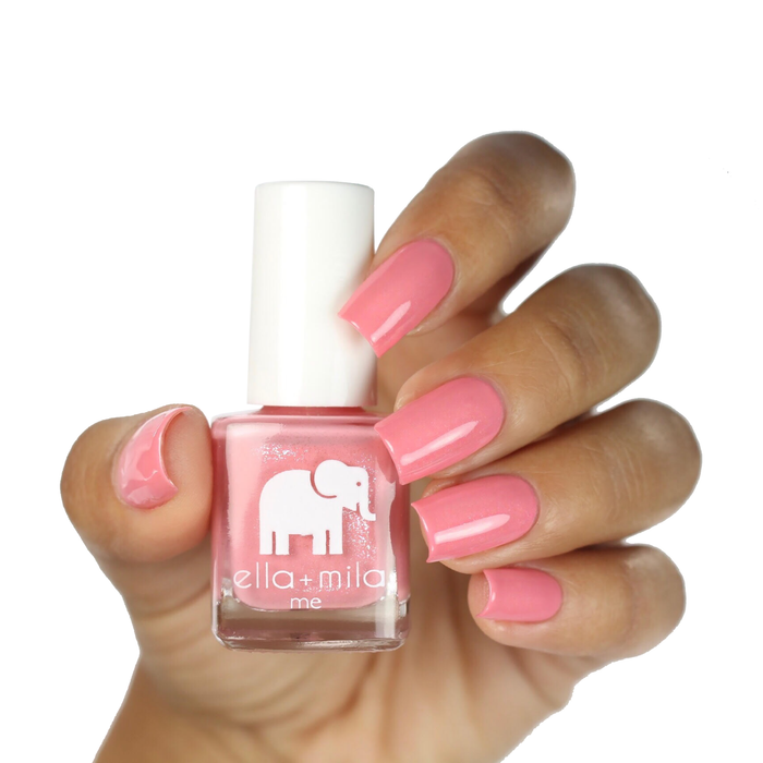 Cotton Candy peachy pink shimmer nail polish on a deep skin tone, hand holding the bottle