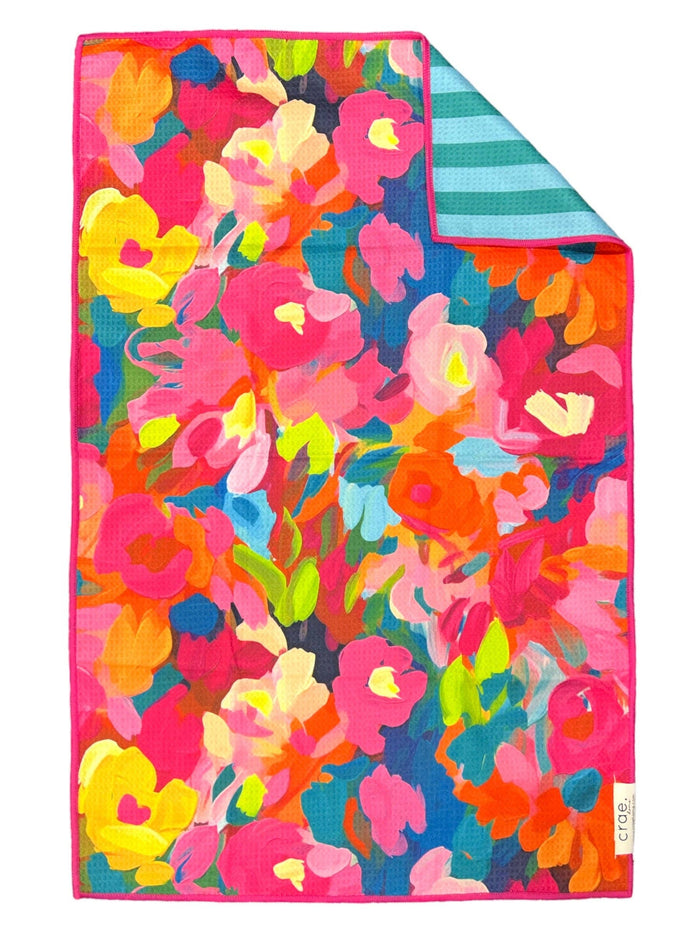 Colorful floral patterned towel with a striped corner on a white background
