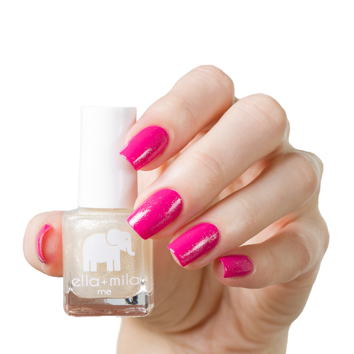 Dipped in Gold shimmer nail polish over a magenta manicure on a light skin tone, holding the bottle