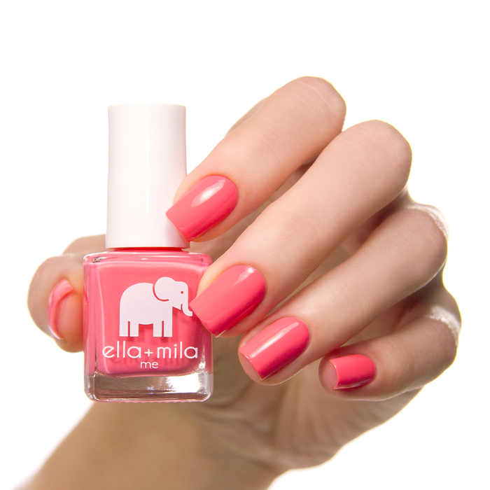 Ella's Pick coral pink nail polish on a medium skin tone, hand holding the bottle