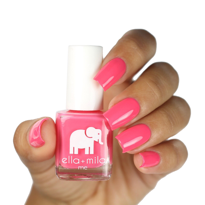 Ella's Pick bright pink coral nail polish on a deep skin tone, hand holding the bottle
