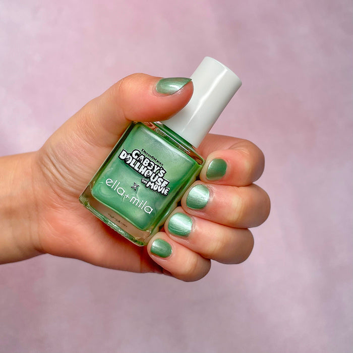 Gabby's Dollhouse mint green shimmer nail polish on a light skin tone, hand holding the bottle