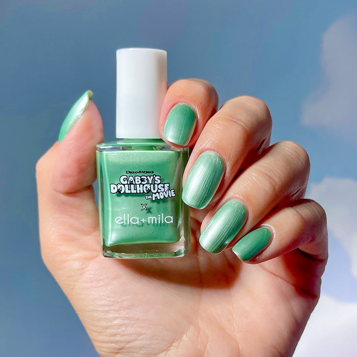 Gabby's Dollhouse mint green shimmer nail polish manicure on a medium skin tone, holding the bottle
