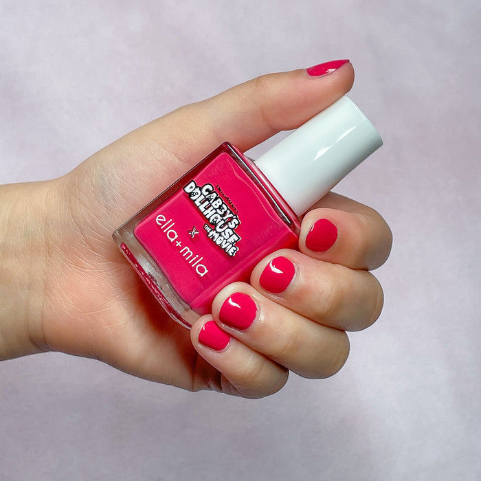 Gabby's Dollhouse hot pink nail polish on a medium skin tone, hand holding the bottle