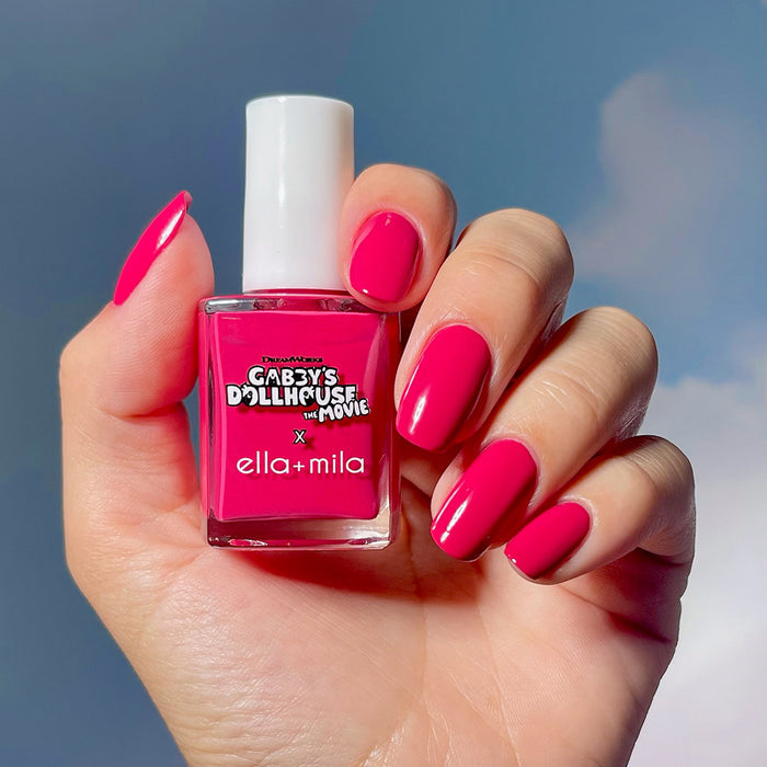 Gabby's Dollhouse hot pink nail polish manicure on a light skin tone, holding the bottle