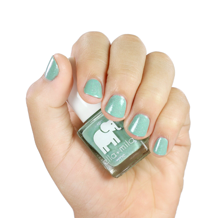 Glitter Me Green teal shimmer nail polish manicure on a light skin tone with the bottle