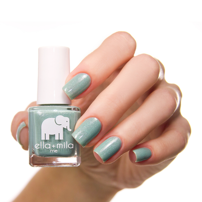 Glitter Me Green teal nail polish on a medium skin tone, hand holding the bottle