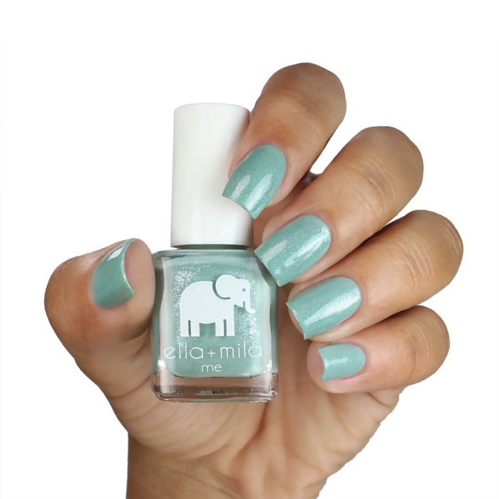 Glitter Me Green teal shimmer nail polish on a deep skin tone, hand holding the bottle