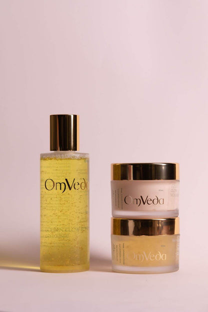 OmVeda golden skincare bottle and matching two-piece cream jars with gold caps