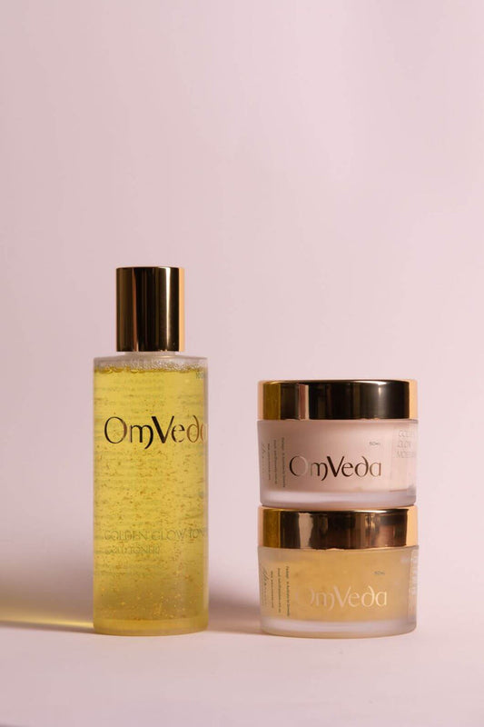 OmVeda golden skincare bottle and matching two-piece cream jars with gold caps