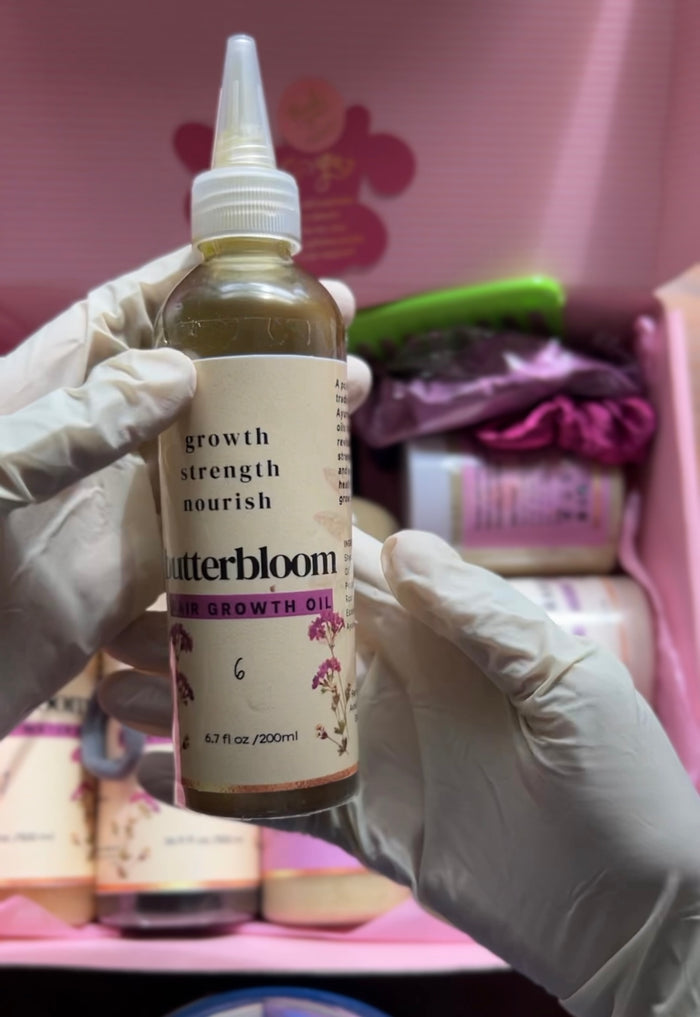 Bottle of butterbloom hair growth oil infused with 21 herbs, showing the clear glass bottle with herbal-infused oil inside.