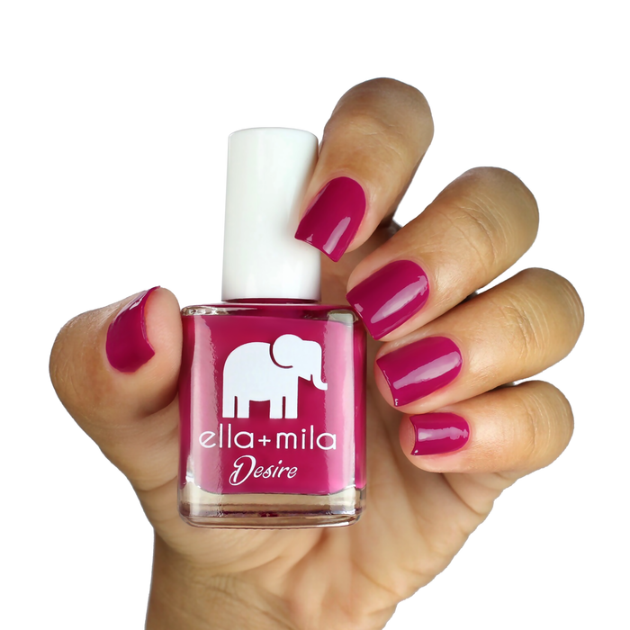 Heartbreaker deep pink nail polish on a medium skin tone, hand holding the bottle