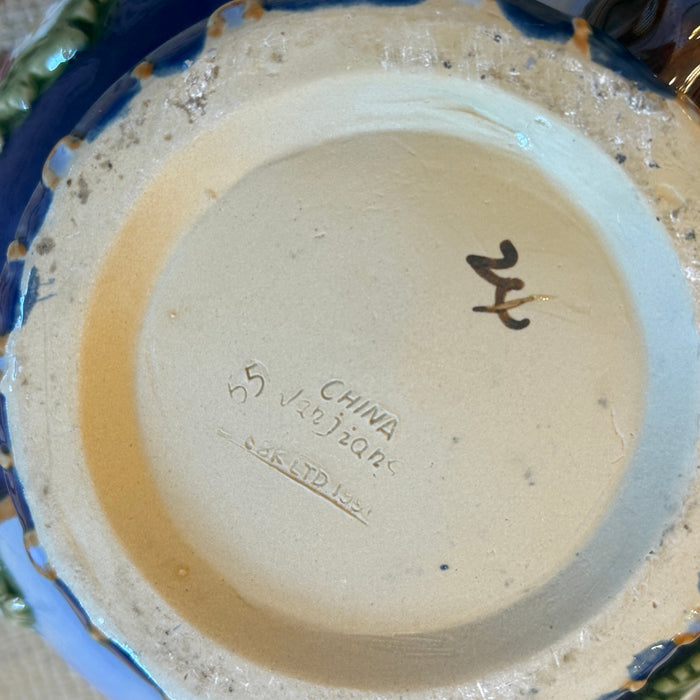 Close-up of a ceramic dish with visible branding and signature