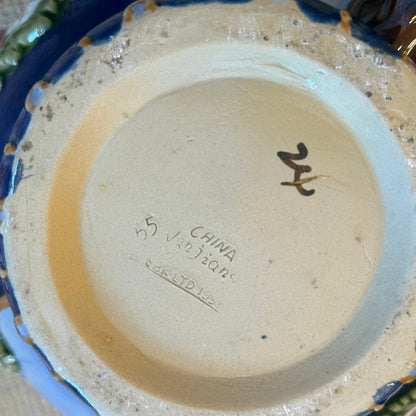 Close-up of a ceramic dish with visible branding and signature