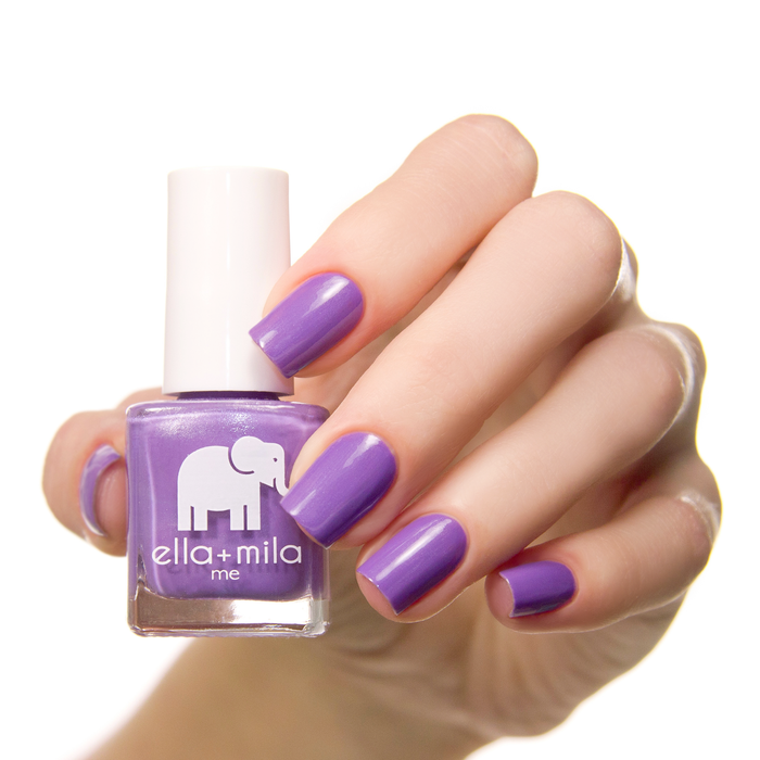Mila's Fave lavender purple nail polish on a medium skin tone, hand holding the bottle