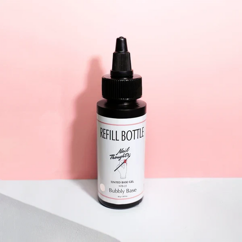 A bottle labeled 'Bubbly Base' with a dropper, placed against a pink background.