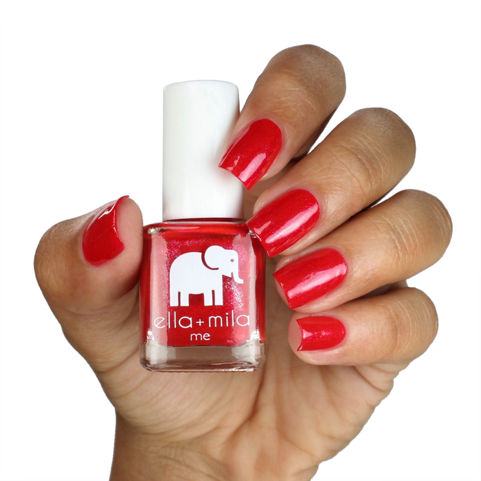 No Place Like Home shimmery red nail polish on a deep skin tone, hand holding the bottle