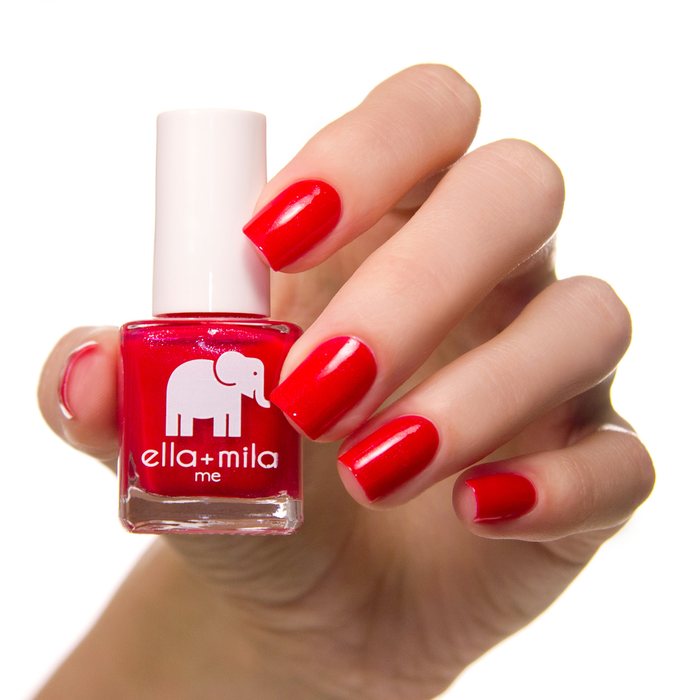 No Place Like Home ruby red nail polish on a medium skin tone, hand holding the bottle