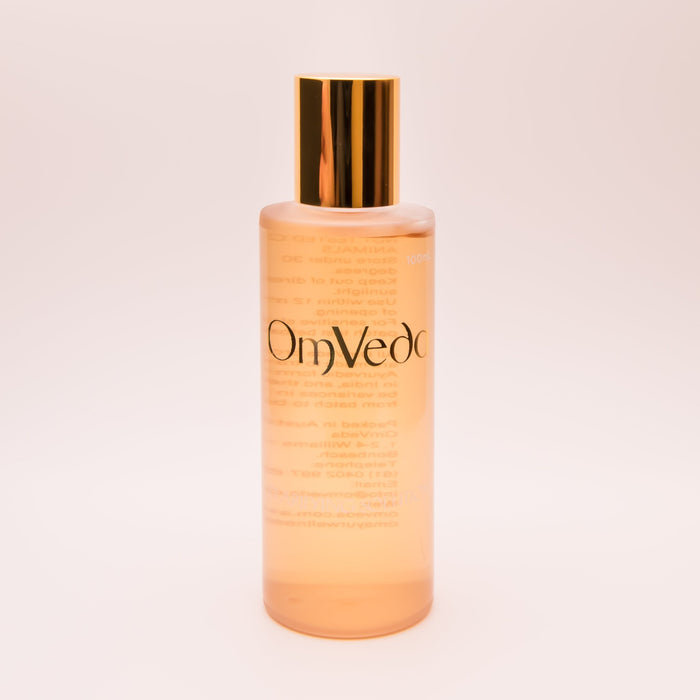OmVeda clarifying solution 100ml translucent amber bottle with gold cap, front view
