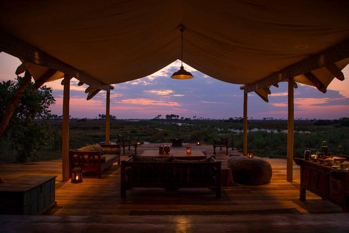 Dining area under a large canopy with a sunset view