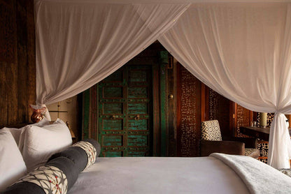 Bed with canopy in a room with wooden walls and furniture.