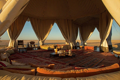 Luxury tented accommodation with outdoor furniture and decor in a desert setting