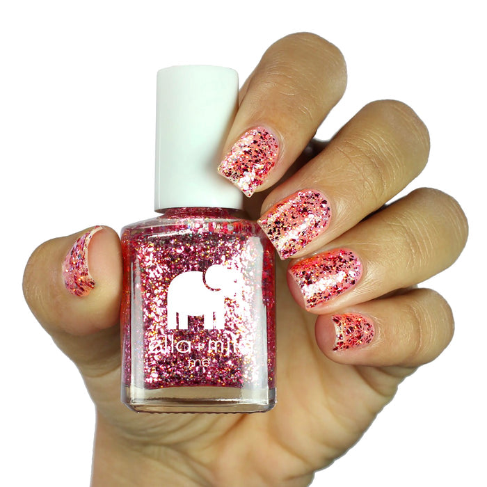 Starbright rose gold glitter nail polish on a medium skin tone, hand holding the bottle