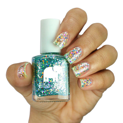 Starlight teal glitter nail polish on a medium skin tone, hand holding the bottle