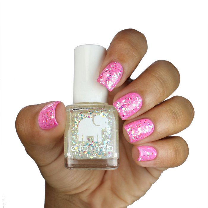 Twinkle Twinkle glitter nail polish layered over pink on a light skin tone, hand holding the bottle