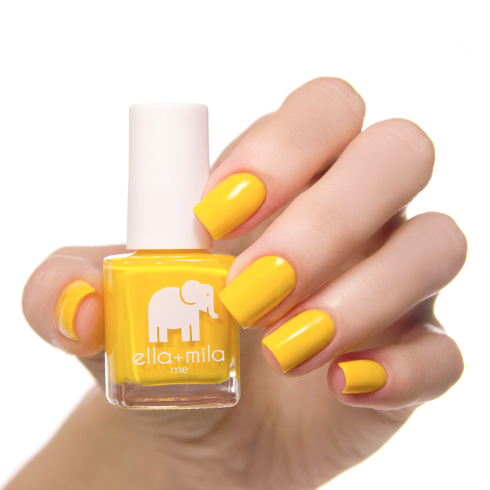 Wheels on the Bus sunshine yellow nail polish on a medium skin tone, hand holding the bottle