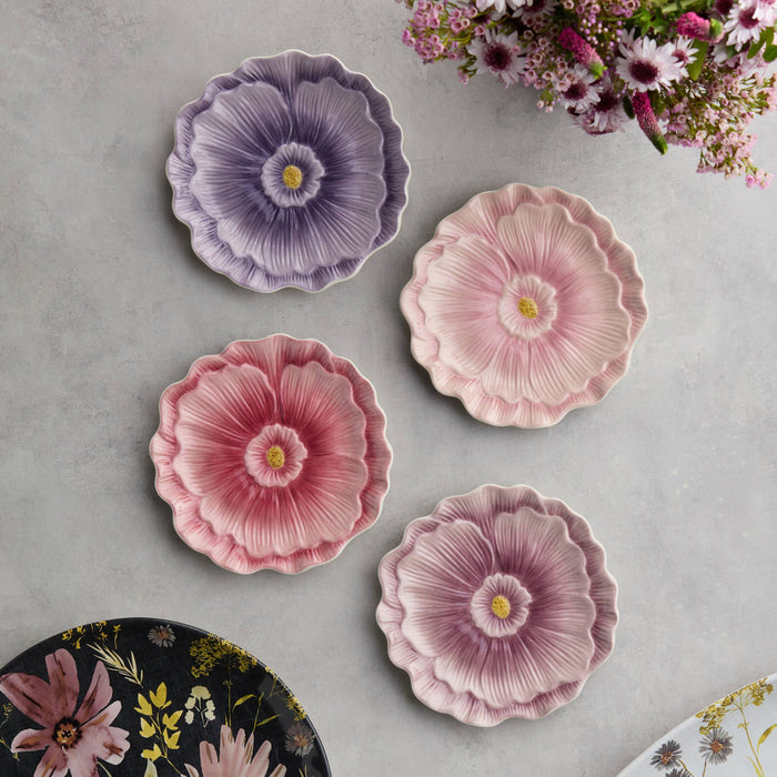 Floral-patterned ceramic plates on a gray surface with flowers in the background