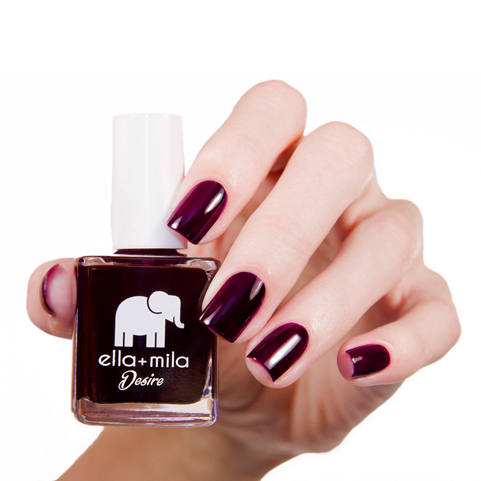Wine Me Up wine red-purple nail polish manicure on a light skin tone with the bottle